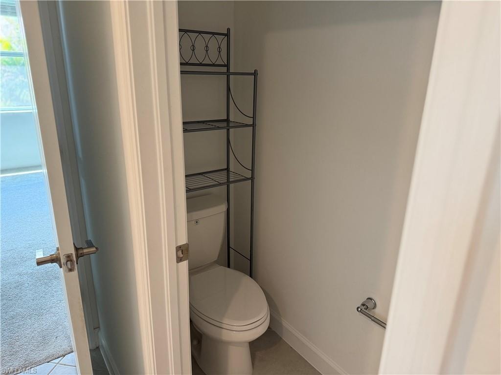 Private water closet featuring a standard toilet, light-toned wall paint, and a metal towel bar