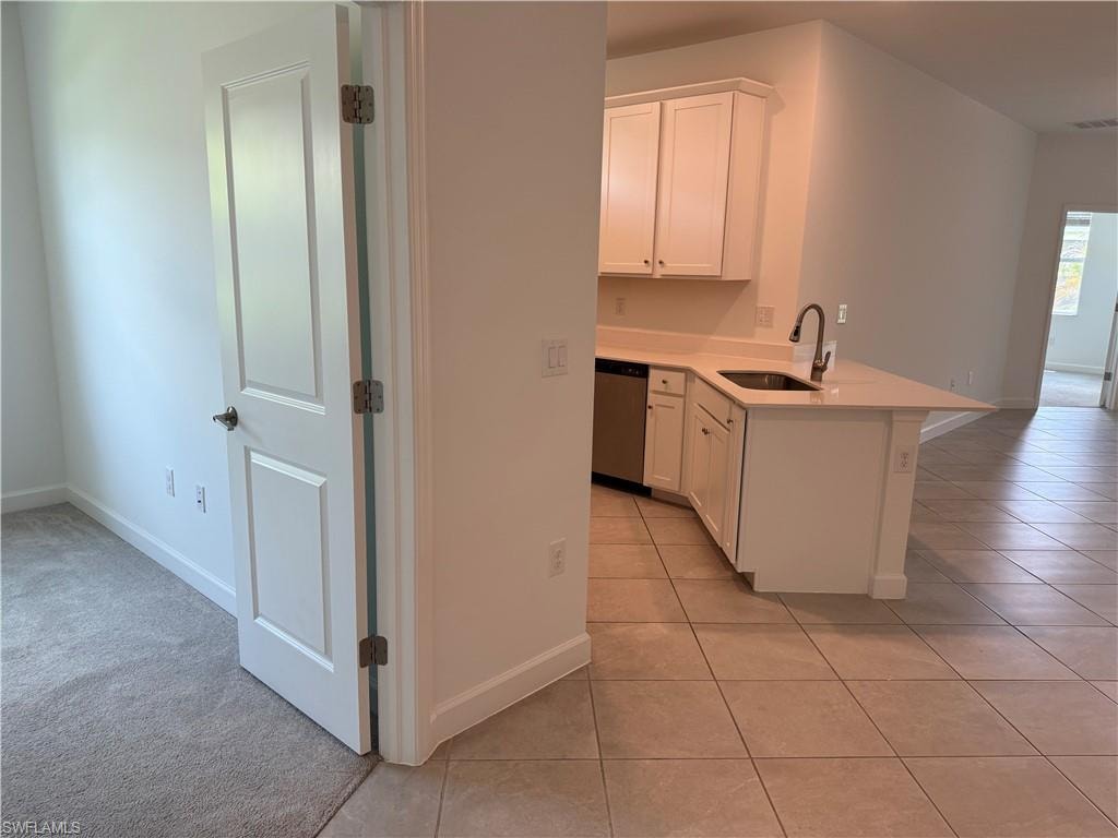 Kitchen area featuring white cabinetry, a light-toned countertop, and a stainless steel sink with a gooseneck faucet