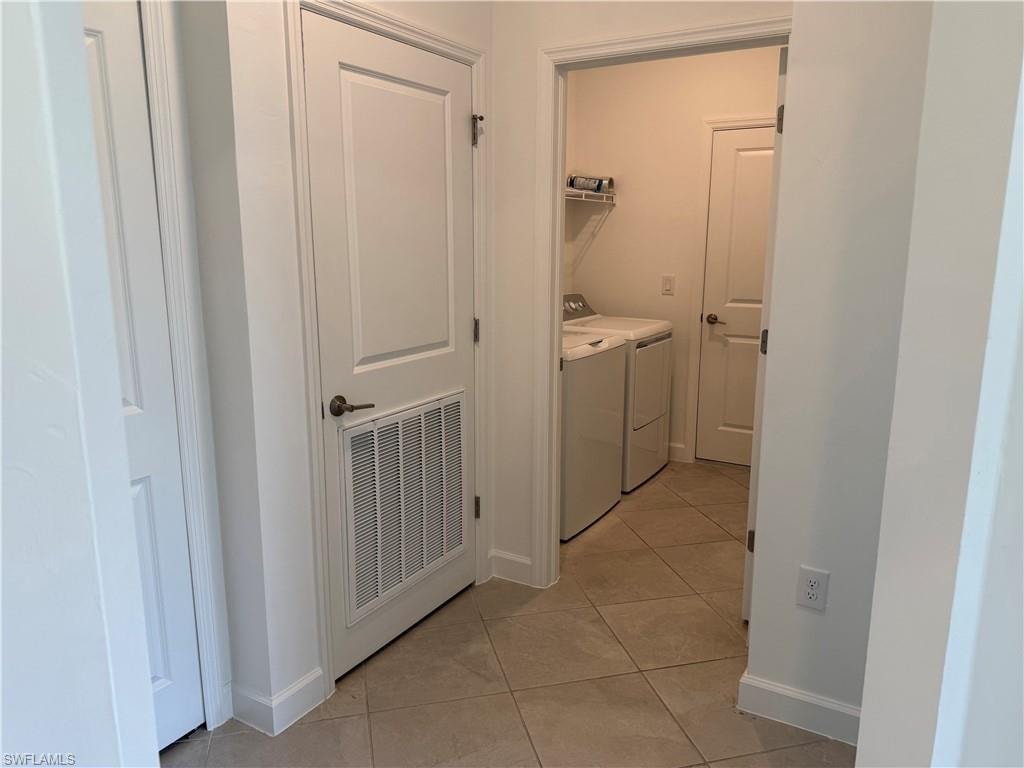 Dedicated laundry area featuring tile flooring, white walls, and a built-in wire shelf