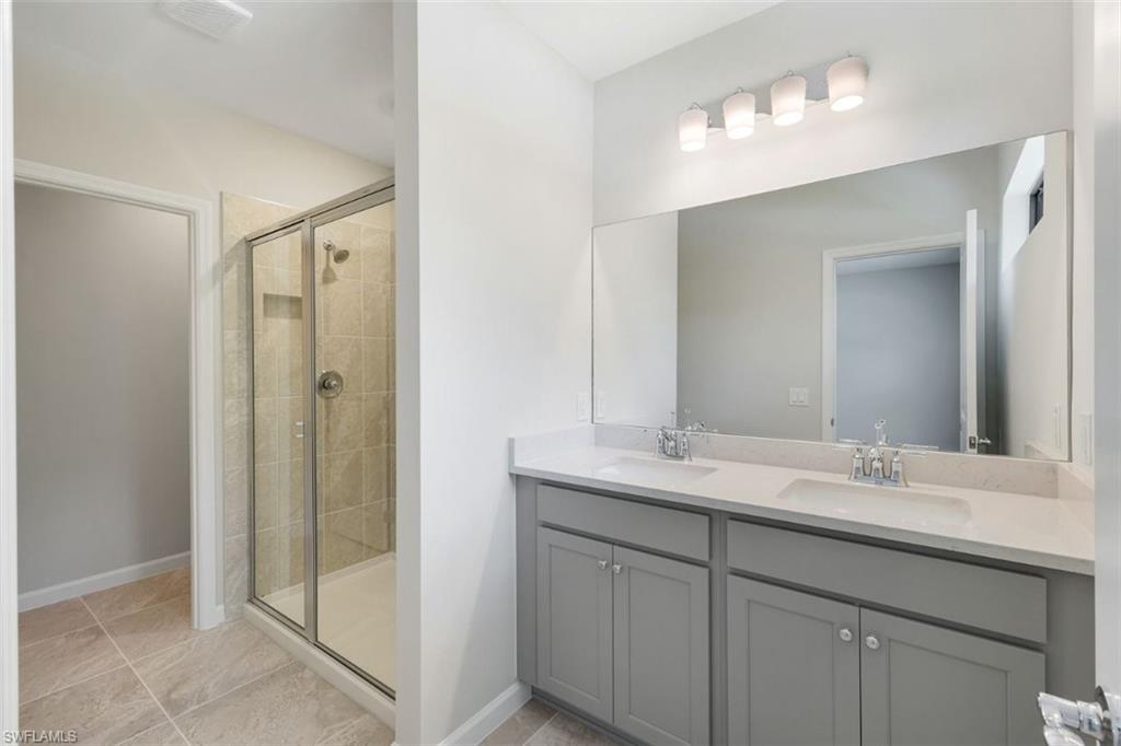 Primary Bathroom featuring a dual-sink vanity with light gray cabinetry, a full-width mirror, and a four-light fixture