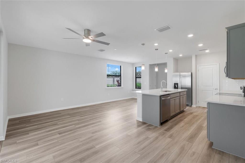 Spacious open-concept living area featuring wood-finish flooring, a contemporary ceiling fan, and recessed lighting