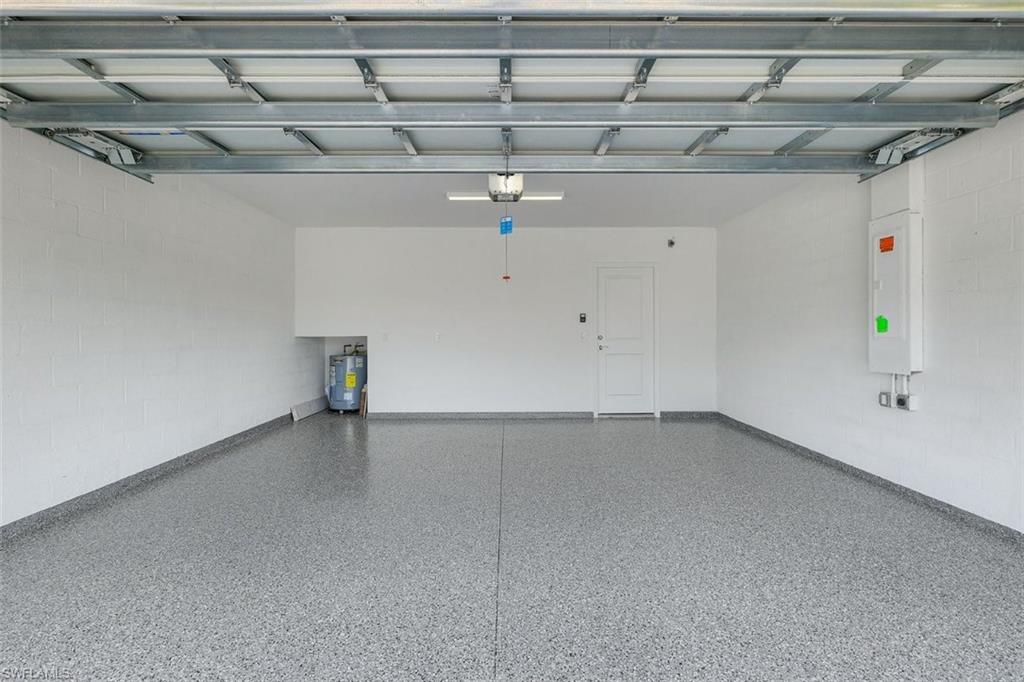 Spacious 2 car garage featuring a durable epoxy-coated floor, painted block walls, and an overhead garage door mechanism