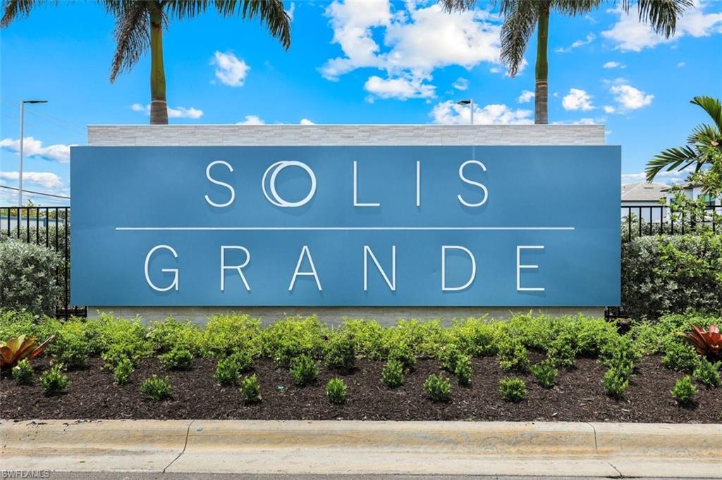 Community entrance sign featuring a blue panel with white lettering, a stone-finish cap, and lush landscaping