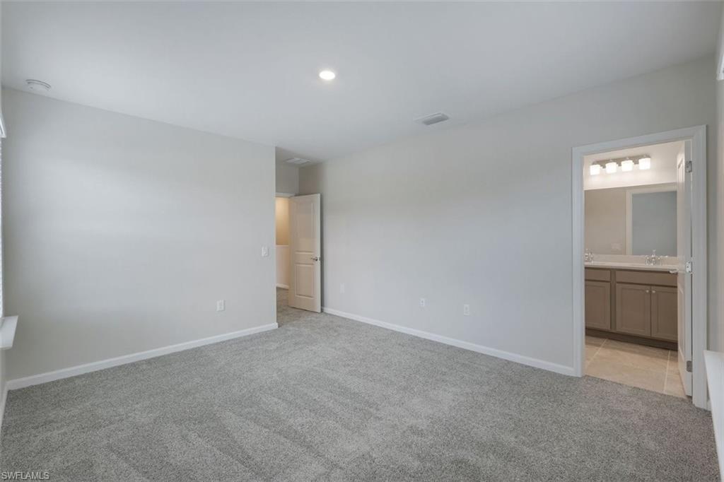 Primary bedroom with plush gray carpeting and light gray walls