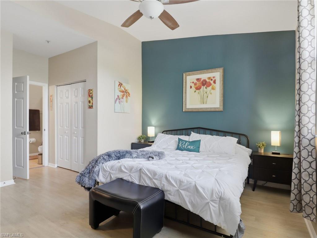 Spacious room featuring vaulted ceilings, wood-finish flooring, a ceiling fan, and a painted accent wall