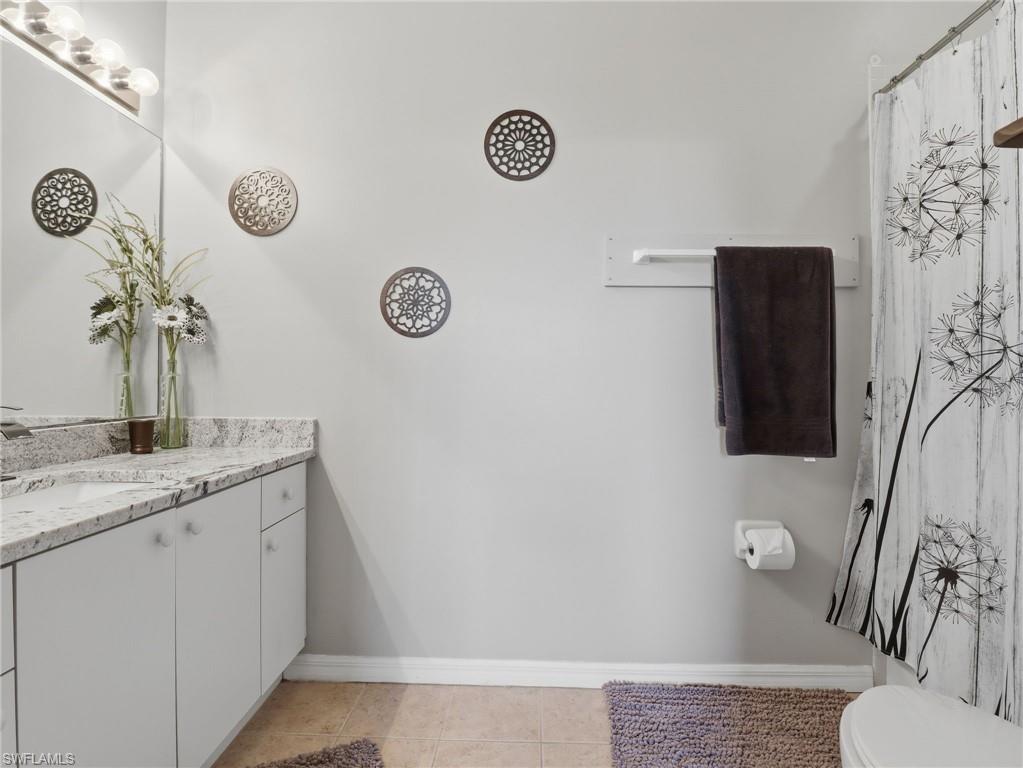 Vanity featuring a solid surface countertop, undermount sink, and four-bulb light fixture