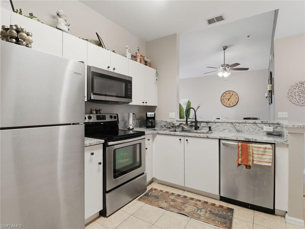Kitchen featuring white cabinetry, stainless steel appliances, speckled stone countertops, and a black gooseneck faucet