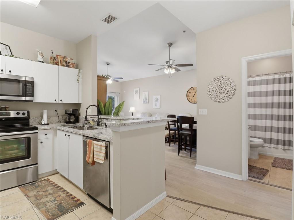 Kitchen featuring white cabinetry, stainless steel appliances, a bar-height counter, and granite-finish countertops