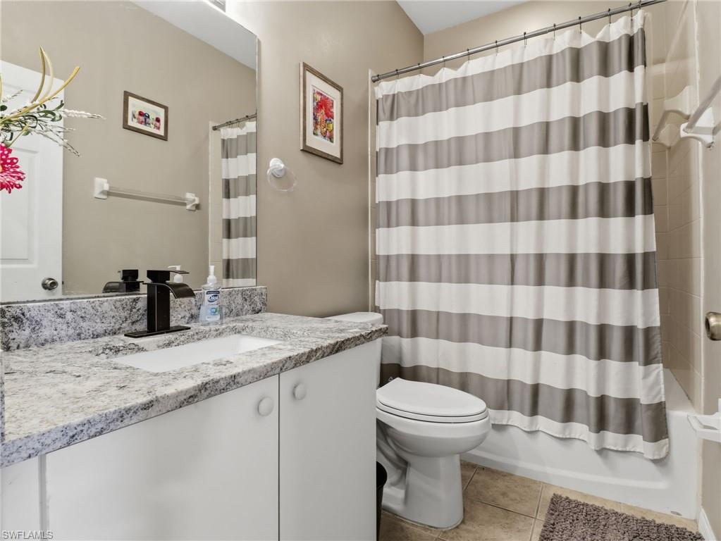Bathroom featuring a white vanity with a light-toned patterned countertop, an undermount sink, and a dark-finish faucet