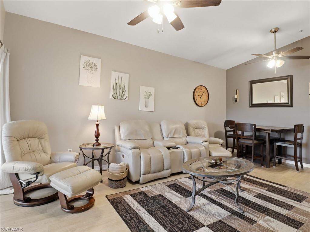 Recessed lighting and ceiling fans illuminate this open-concept living space featuring light-toned flooring, neutral wall finishes, and a dedicated dining area