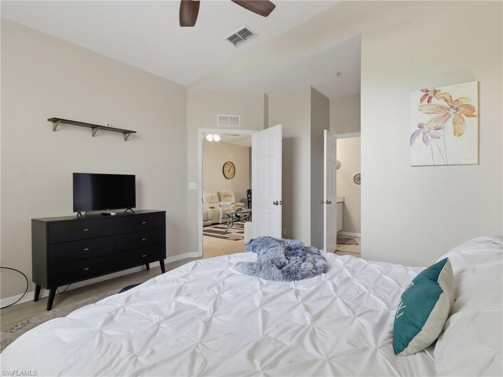 Bedroom featuring vaulted ceilings, a ceiling fan, light neutral wall paint, and a built-in wall shelf
