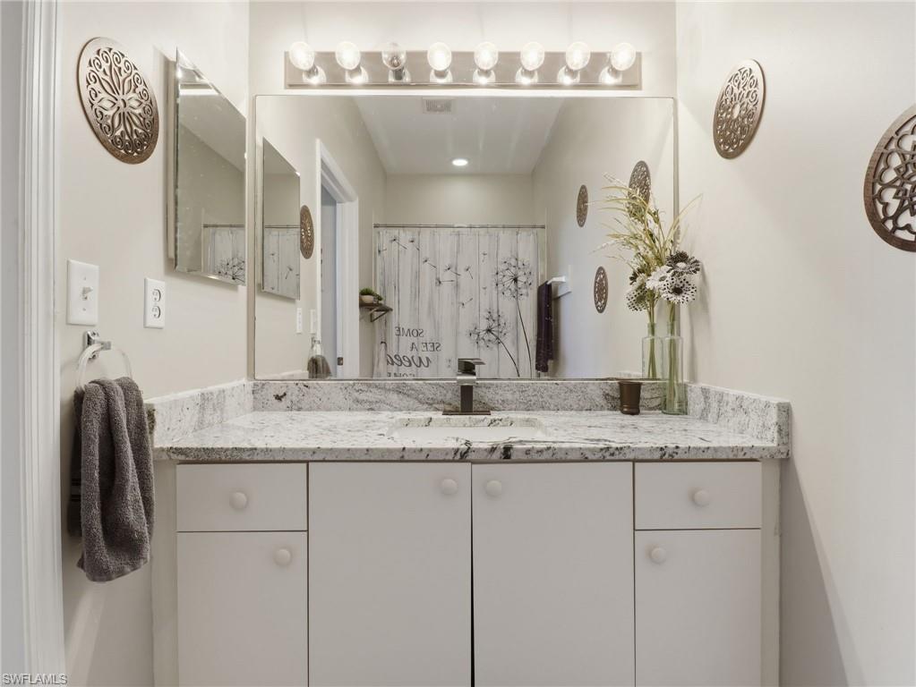 Bathroom vanity featuring a quartz countertop with an integrated sink, white cabinetry, and a large wall-mounted mirror