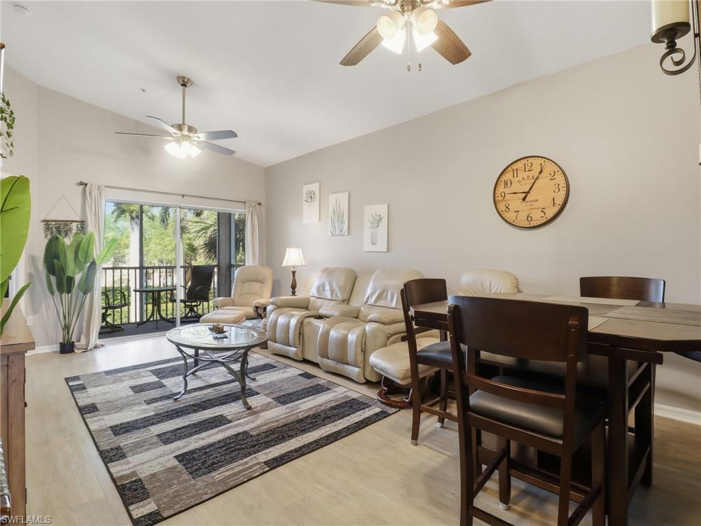 Open-concept living space featuring light wood-finish flooring, vaulted ceilings, and dual ceiling fans with integrated lighting