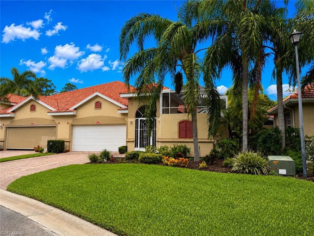 Stucco exterior residence featuring a terracotta tile roof and an attached two-car garage and beautiful landscaping.