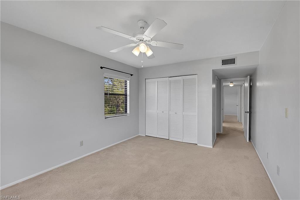 Unfurnished bedroom with light colored carpet, a closet, and ceiling fan