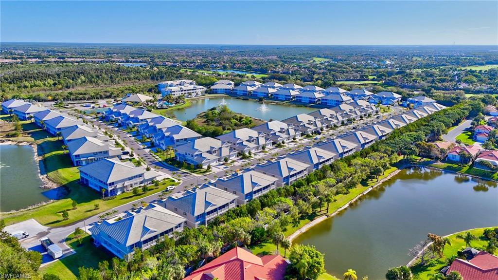 Expansive community featuring multiple residential buildings with light-colored roofs, surrounded by waterways