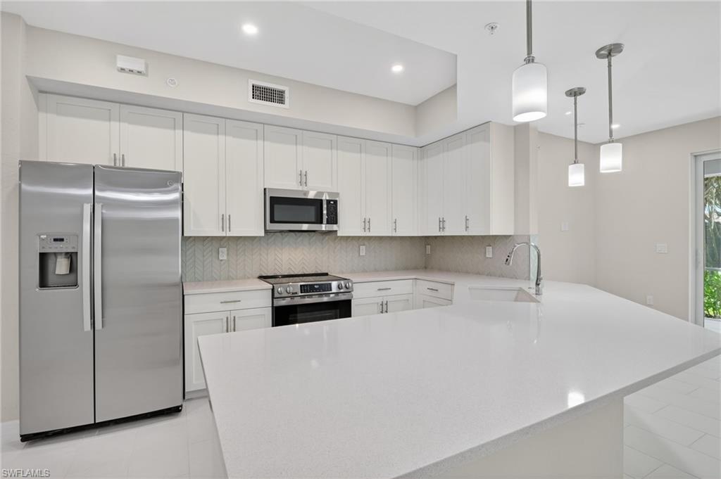 Kitchen with white shaker cabinetry, stainless steel appliances, and a light-toned countertop