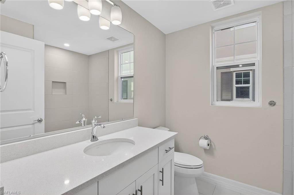Contemporary bathroom featuring a white vanity with a light-toned countertop, a large wall-mounted mirror, and a modern chrome faucet