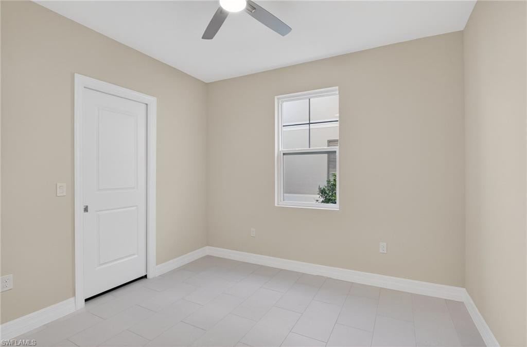Bright room featuring a ceiling fan, light-toned walls, and tile flooring