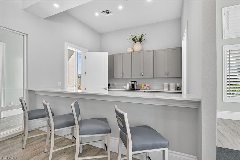 Breakfast bar with a light-toned countertop, under-cabinet storage, recessed lighting, and wood-finish flooring