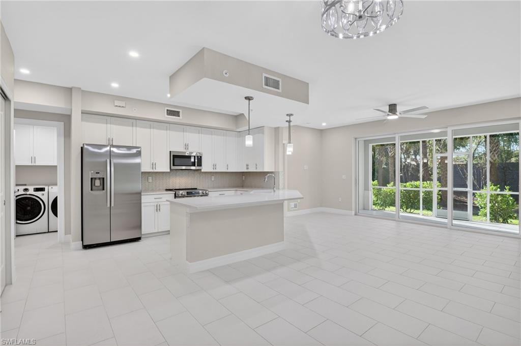 Open-concept living space with a contemporary kitchen, large format tile flooring, and extensive sliding glass doors