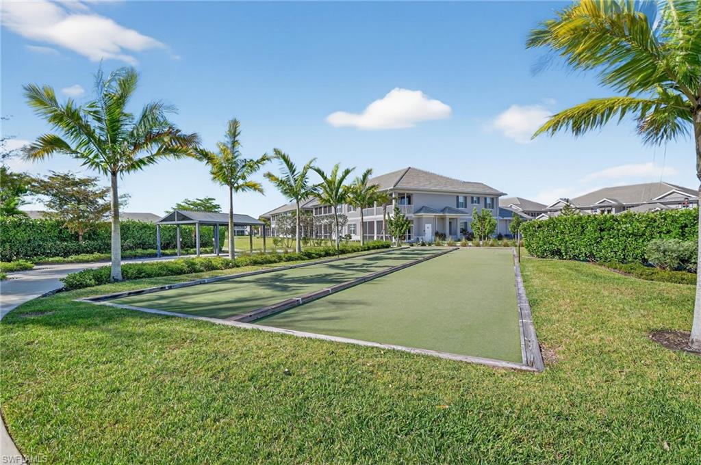 Manicured bocce ball court framed by lush green grass and mature palm trees