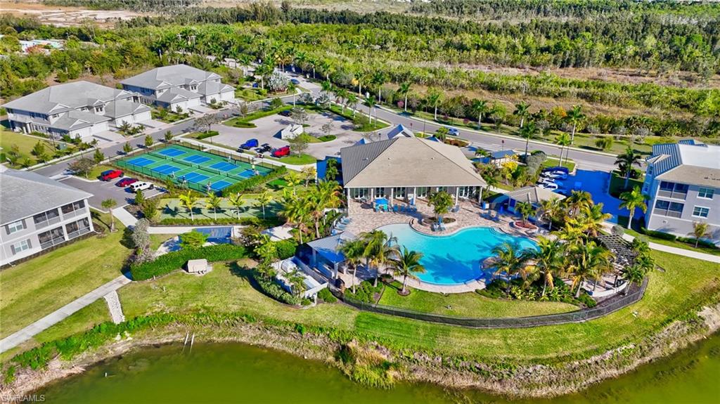 Community clubhouse with a large freeform swimming pool, extensive patio space, and surrounding palm trees