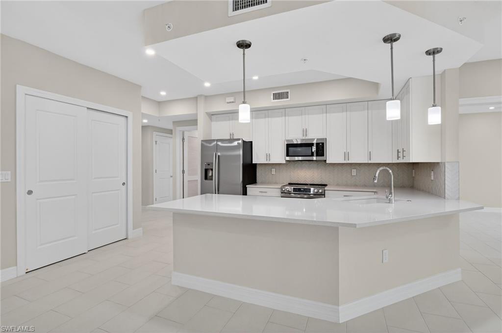 Kitchen featuring a large island with a surface, stainless steel appliances, white cabinetry, and recessed lighting