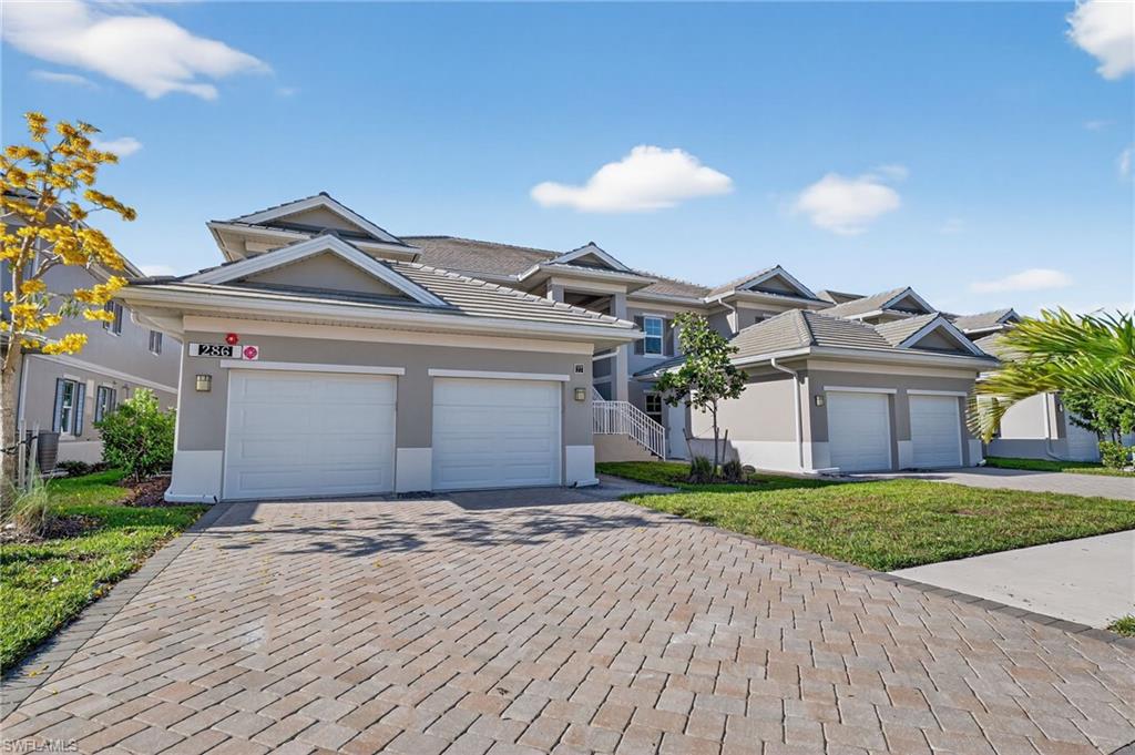 Multi-story residence featuring a stucco exterior with decorative gables, a tile roof, and a two-car garage with white doors