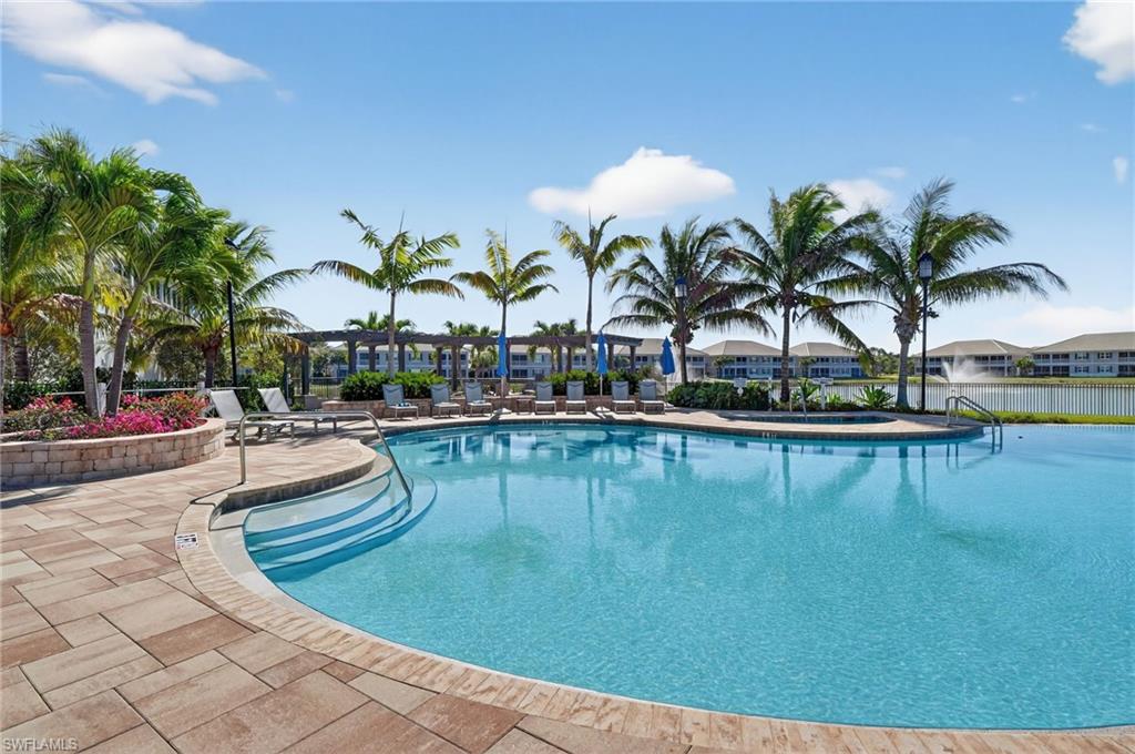 Resort-style swimming pool featuring integrated steps, surrounding paver patio, and mature palm trees