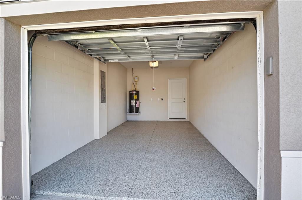 Spacious garage featuring an epoxy-coated concrete floor, painted block walls, and a recessed water heater