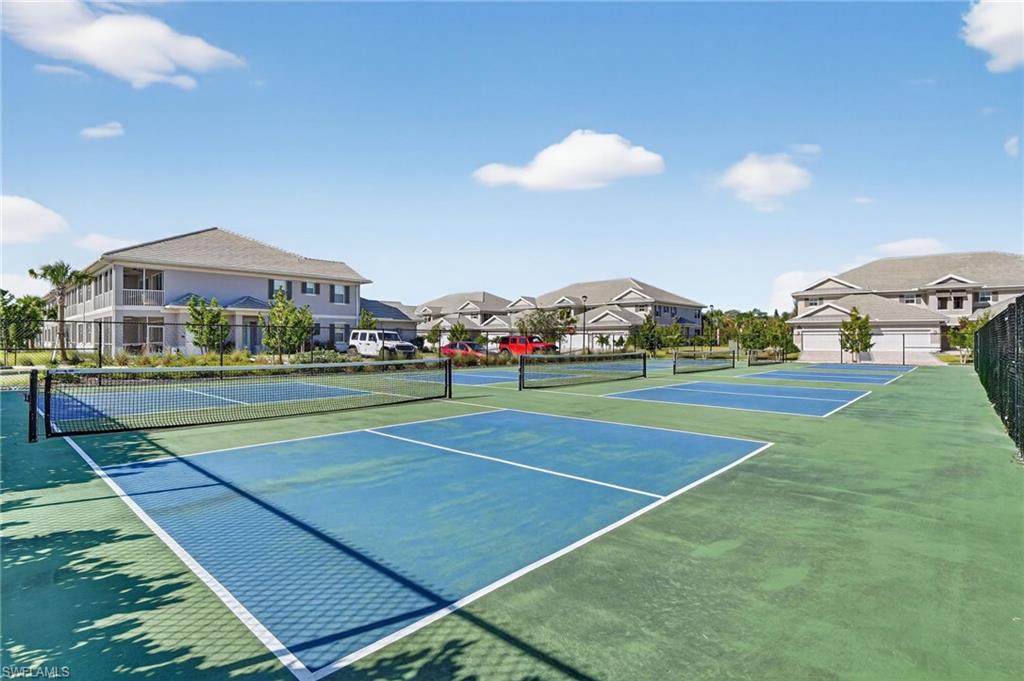 Multiple hard courts featuring blue playing surfaces and green surrounds, equipped with nets