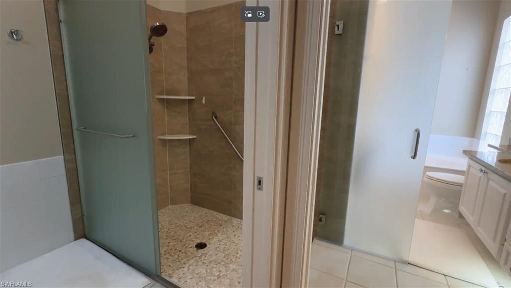 Spacious en-suite primary bath featuring dual vanities, a soaking tub, a unique walk-through shower with dual entrances, and two private water closets for added comfort and convenience