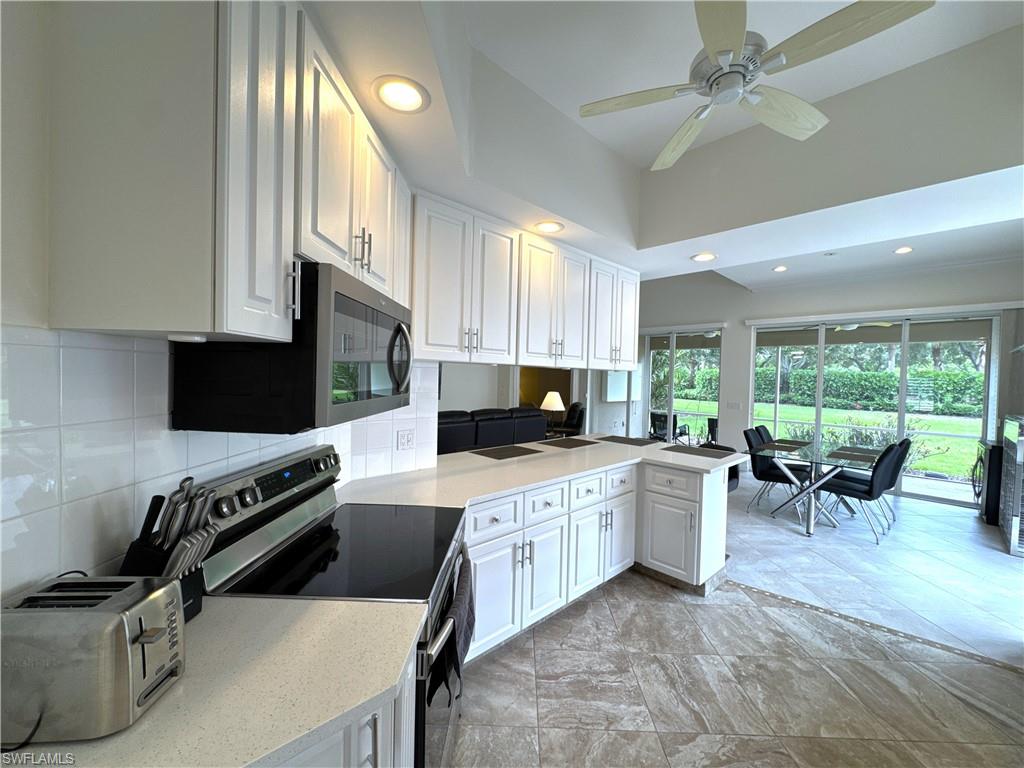 Kitchen leads to the dining area overlooking the screen lanai and landscaped backyard.