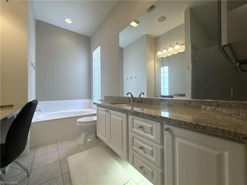 Spacious en-suite primary bath featuring dual vanities, a soaking tub, a unique walk-through shower with dual entrances, and two private water closets for added comfort and convenience