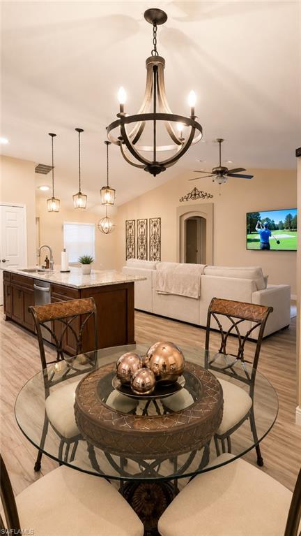 Open concept living space featuring a cathedral ceiling with a wood-finish chandelier, recessed lighting, and wood-finish flooring