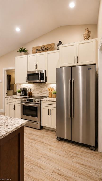 Modern kitchen featuring stainless steel appliances, light-toned cabinetry, light-colored countertops, a tile backsplash, and wood-finish flooring