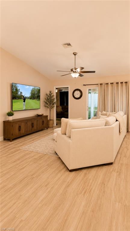 Open-concept living area featuring a vaulted ceiling and light wood-finish flooring