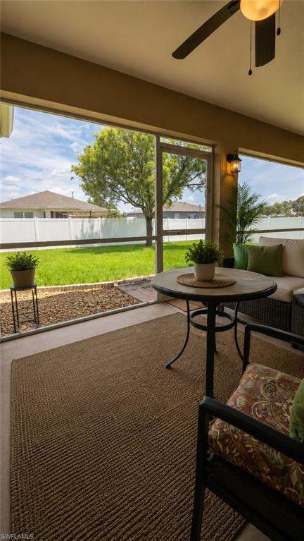 Screened patio featuring a ceiling fan with integrated lighting, wall sconce lighting, and views of a spacious lawn