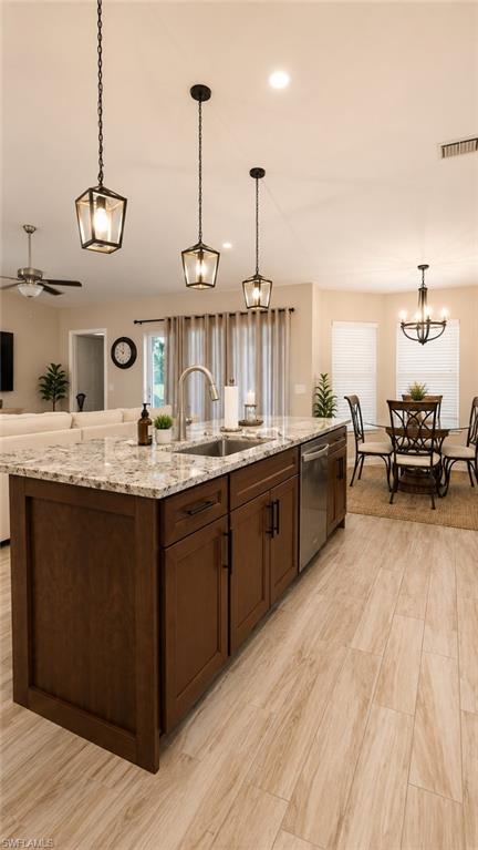 Kitchen island featuring wood-finish cabinetry with black hardware, an undermount sink with a gooseneck faucet, and a light-toned countertop