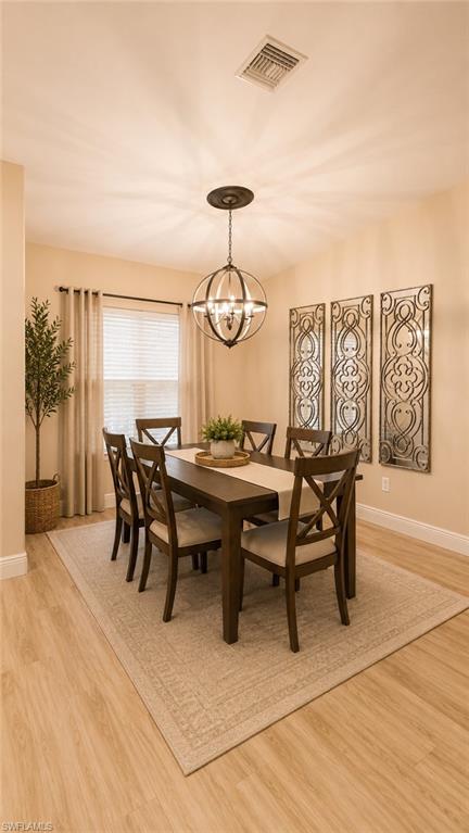 Dining area featuring wood-finish flooring, a large window with blinds and drapes, and a contemporary spherical chandelier