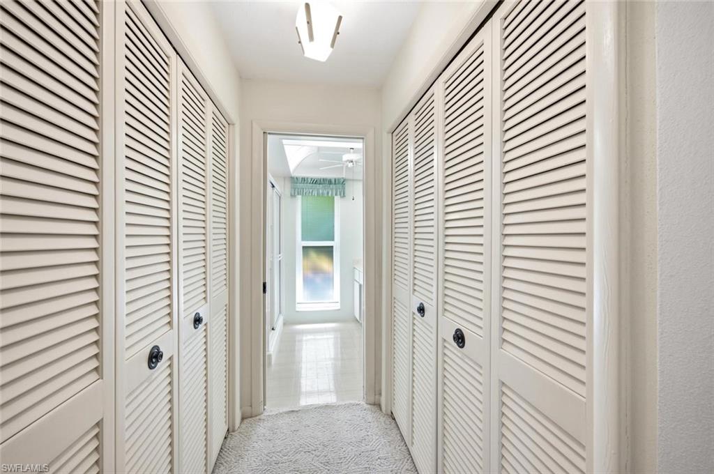 Hallway featuring louvered bi-fold doors, recessed lighting, and tile flooring extending towards a window