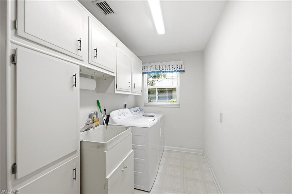 Dedicated laundry space featuring extensive white cabinetry, a utility sink, and ample overhead storage