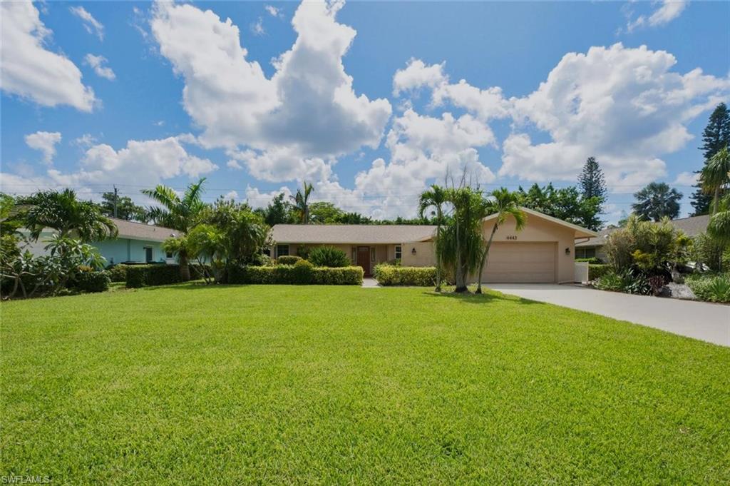 Expansive front lawn with mature landscaping and established palm trees