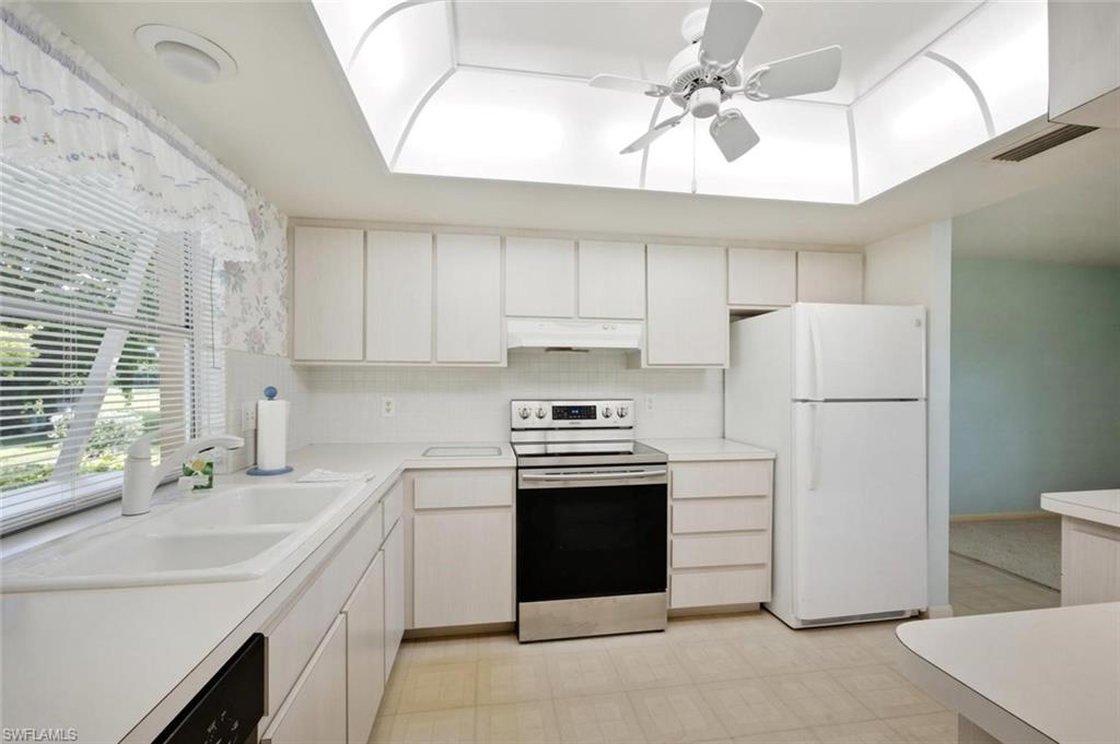 Kitchen featuring white cabinetry, a double basin sink, tile flooring, and a stainless steel and black range