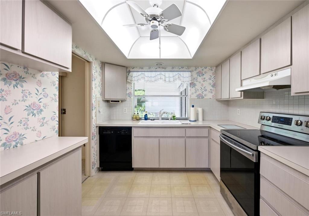 Bright kitchen featuring a skylight with a ceiling fan, white cabinetry, white countertops, and a full suite of appliances including a black dishwasher and a stainless steel range with a black cooktop