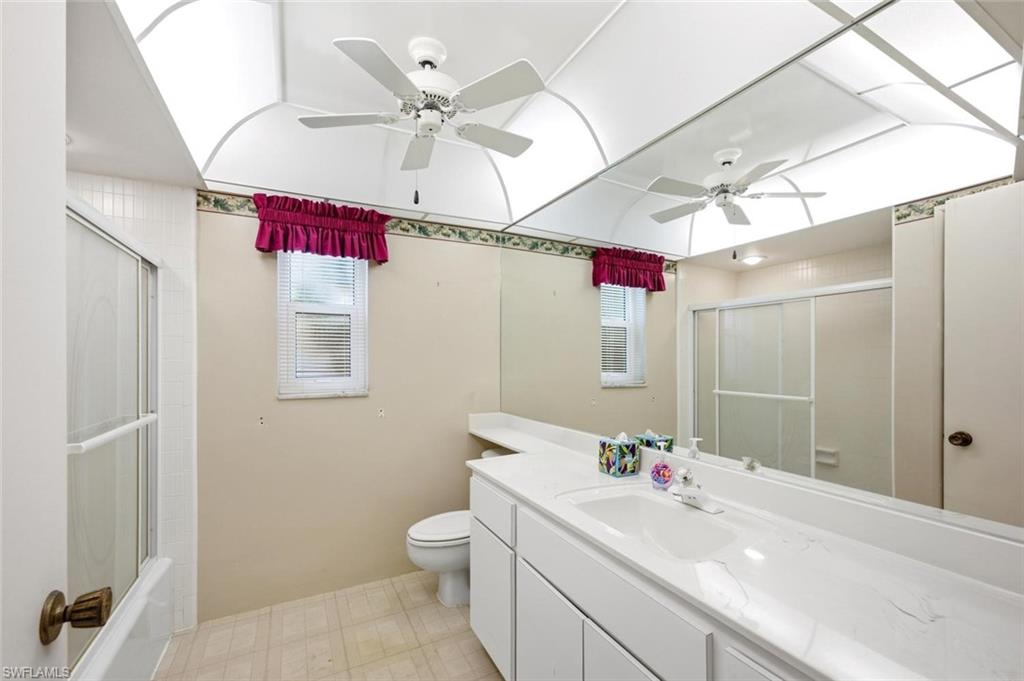 Bathroom featuring a broad vanity with integrated sink, a large wall-mounted mirror, and a shower with sliding glass doors