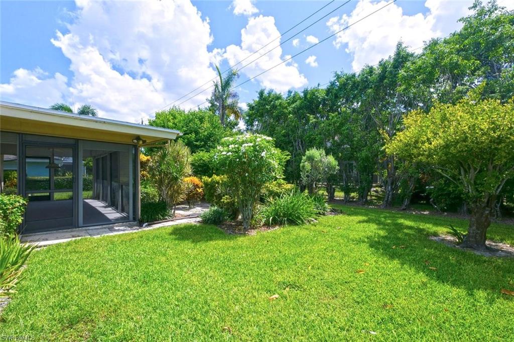Screened patio with a concrete slab, overlooking a lush green lawn and mature landscaping