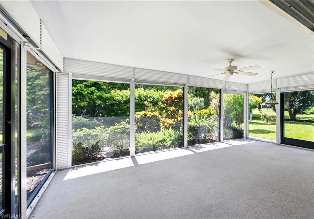 Spacious screened enclosure featuring ample natural light, a ceiling fan, a pendant light fixture, and a durable flooring surface