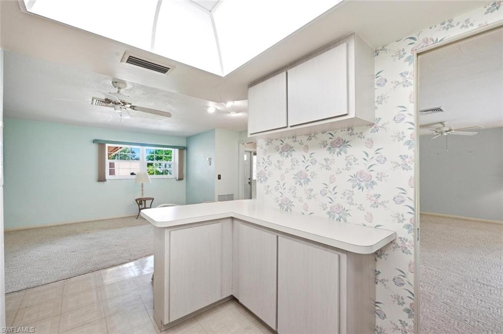 Kitchenette with white cabinetry and countertop, illuminated by a skylight